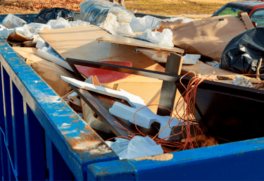 alt="Construction dumpster filled with scrap wood and renovation materials from commercial cleanout"