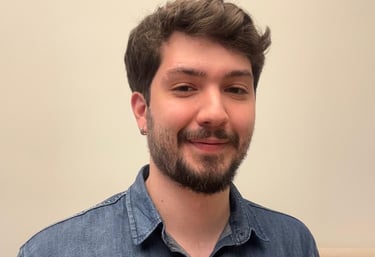 Foto do psicólogo do peito pra cima. Um homem branco com barba e cabelos castanhos, de camisa azul.