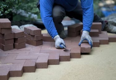 a person laying red brick in a herringbone pattern