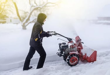 a person using a snow blower to clear snow from the driveway