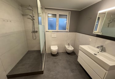ein modernes Bad, frisch saniert, große beghehbare Dusche, WC, Bidet und Waschbecken.