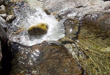 water falling on rocks. sun reflecting off water.