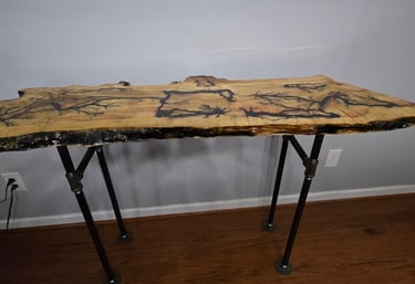 Handcrafted live edge console table wood burning patterns and industrial pipe legs.