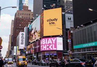An urban cityscape featuring a bustling commercial area with large advertisements and billboards. Prominent brand logos like Coca-Cola are displayed on the large screens. The area is lively with various shops and brands like Cineplex, Adidas, and Winners visible. There is a decorative sculpture resembling a Christmas tree made of white spherical structures in the foreground.