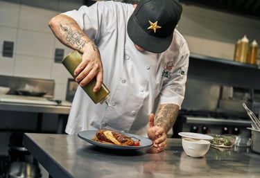 A man with a hat preparing dinner in an industrial kitchen
