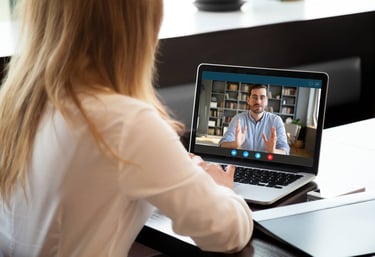 a woman sitting at a table with a laptop computer screen