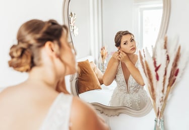 Mariée qui se prépare devant un miroir et attache une boucle d'oreille.