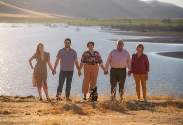 Family portrait photographer in Visalia capturing a group by a lake at sunset.