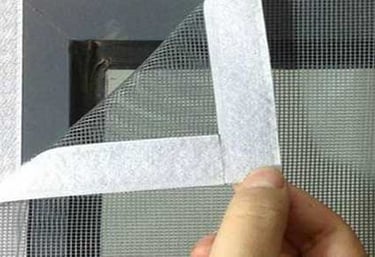 A technician carefully fitting a mosquito net on a window in a bright Sarjapur home.