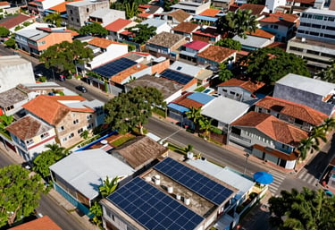 An aerial view of a vibrant Brazilian city neighborhood with several houses featuring solar panel installations, bright day lighting, eco-friendly urban scene.