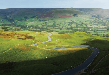 a winding road in the hills of a green valley