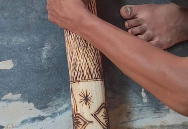 Artisan polishing a bamboo handicraft engraved with traditional tribal designs using an electric too