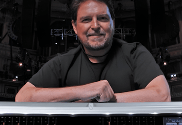 Jon Lemon smiling  and leaning on mixing desk.