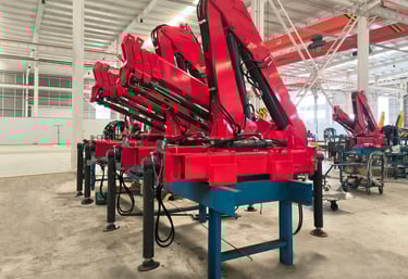Production line: Red SQZ68B.3 (3.2T) articulating knuckle boom cranes on blue stands, pre-vehicle mounting.