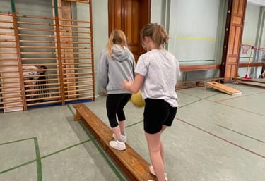 image de 2 élèves marchant sur un banc dans la salle de gymnastique