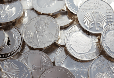 a pile of coins with a person holding a coin
