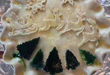 A festive homemade Christmas pie crust decorated with dough reindeer, sleigh, and green trees.