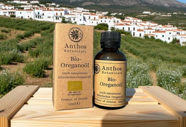 a bottle of organic oregano essential oil in front of a greek village