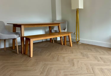 A medium oak colour herringbone LVT floor with a table and chairs