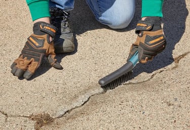 Prepping driveway for sealcoat and crack repair by removing debris