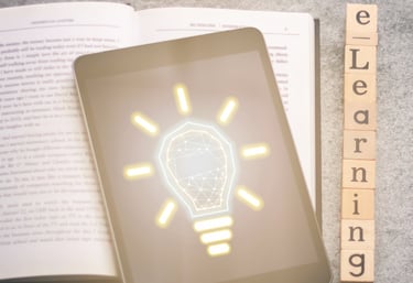A tablet computer sits on an open book displays the image of a shining lightbulb with a brain in it.