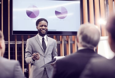 A smiling man in a business suit giving a presentation.