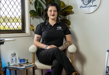 Professional photographer sitting in a studio with Brush and Shutter branding and photography gear.