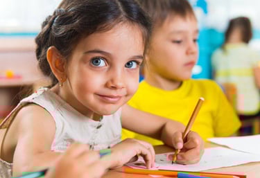 a young girl is sitting at a table with pencils and pencils