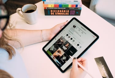 Pessoa usando tablet com caneta digital para navegar nas redes sociais em uma mesa de trabalho.