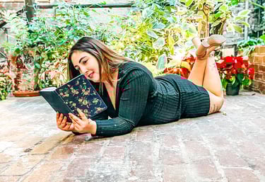 Patricia laying on the floor in a garden reading a journal