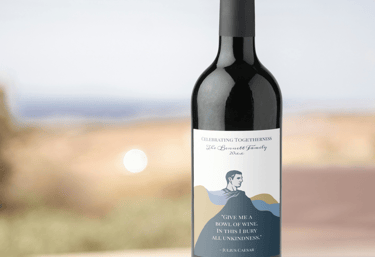 A sleek wine bottle with a custom label featuring a minimalist portrait and a Shakespeare quote.