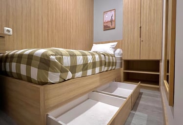 Kamar kos eksklusif dengan single bed, meja belajar, lemari kayu, dan cermin full body di Kos Si Bos