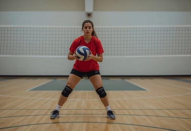 A teenage volleyball player practices skills on an indoor court, focusing on technique