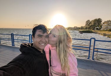 Introduction image of Lennard and Anne on a pier at sunset. The woman kisses the smiling man 