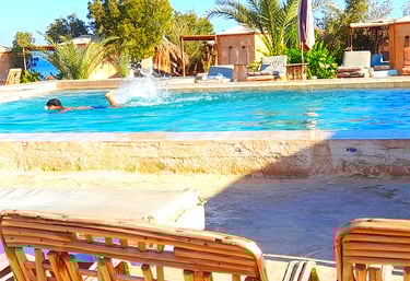 Fiú úszik a medencében, közel a tengerhez és bungalóhoz a beduin csillag Egyiptomban