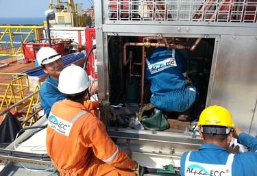 Alpha ECC technicians in safety gear performing HVAC maintenance on an offshore platform.