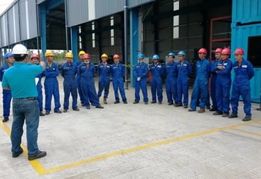 Industrial workers and hard hats attend a safety briefing at a warehouse.