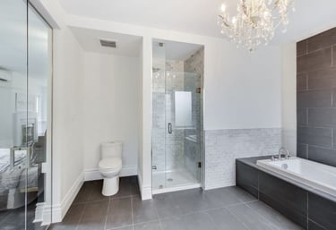 a large master bathroom with a toilet, shower stall, and soaker tub tiled in black