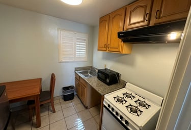 a kitchenette with a stove top oven, sink, microwave and table with a chair