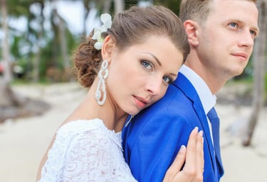 Bride rests on groom shoulder in beach wedding portrait