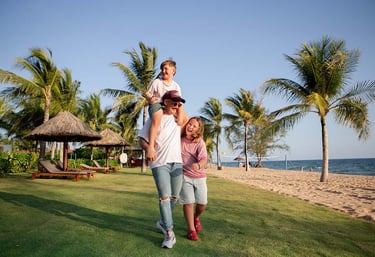 Family photoshoot at Mövenpick Resort Phu Quoc — father carrying son, walking along the lawn