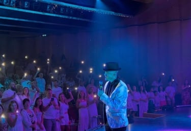 a man in a white shirt and a microphone in front of a crowd