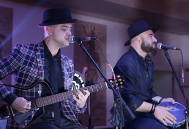 two men playing guitar and singing into a microphone