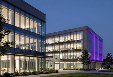 A wide, professional architectural shot of a modern, minimal tech campus at night with violet lights illuminating the glass walls, North American / International.