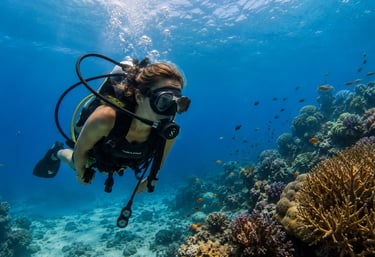 A female scuba diver exploring a vibrant tropical coral reef with colorful fish in clear blue water.