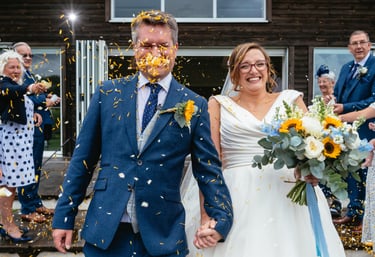 Bride and groom laughing as confetti is thrown at Llanerch Vineyard wedding in South Wales, captured by Owen Mathias