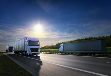a truck driving down a highway with a bright sun shining on the road
