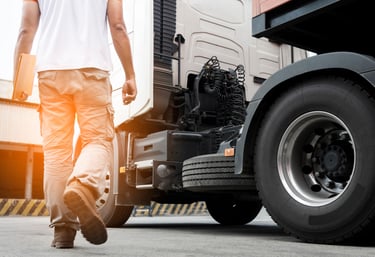 a man walking away from a truck with a large tire