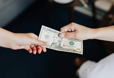 two people holding onto a dollar bill representing blog post about gold ira fees and a guide to understanding gold ira fees