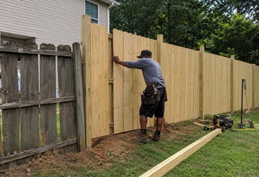 A professional contractor installing a new cedar wood privacy fence in a residential backyard.